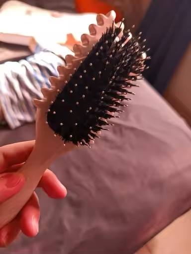 A person holding the ergonomic handle of the hairbrush.